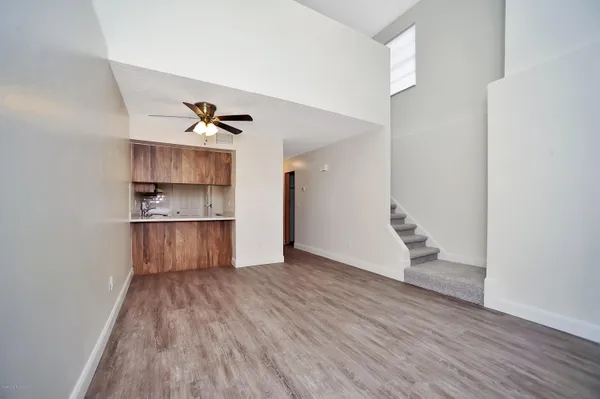 a view of kitchen and empty room with wooden floor