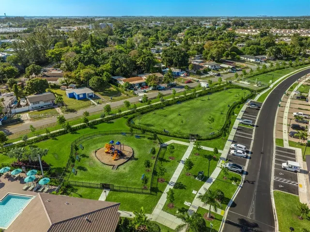an aerial view of a residential houses with outdoor space and trees