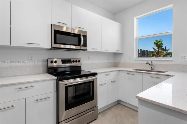 a kitchen with stainless steel appliances a stove microwave and sink