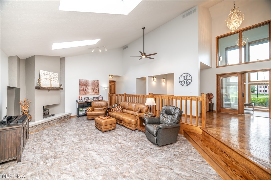 405 Airport Road Northwest Warren, OH 44481 - Photo 10 of 50 Spacious living area featuring high vaulted ceilings, multiple skylights, a prominent fireplace with a substantial stone hearth, and a wood railing overlooking a hardwood entry