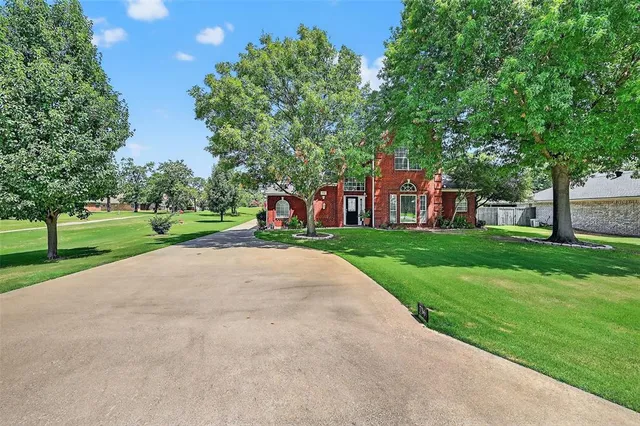 a view of a house with a big yard and large trees