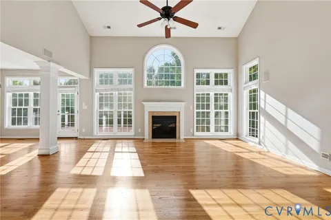 a view of an empty room with wooden floor fireplace and a window