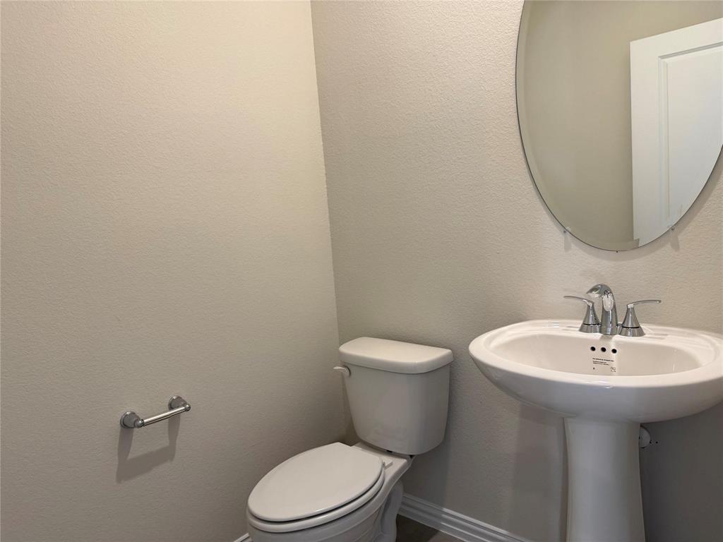 Pedestal sink with chrome-finish faucet and an oval wall mirror