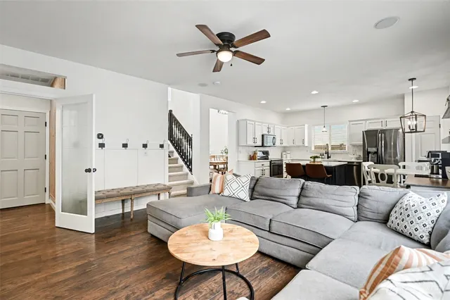 a living room with furniture kitchen view and a wooden floor