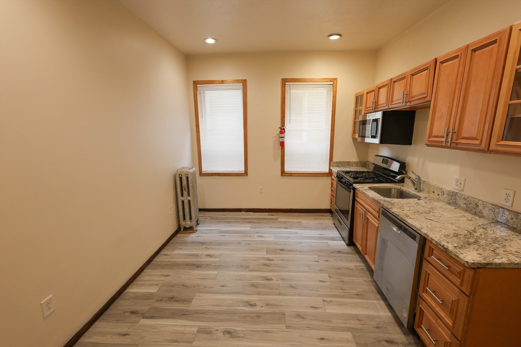 100 Seaver Street, Unit 2 Boston, MA 02121 - Photo 4 of 18 a view of a kitchen with kitchen island granite countertop wooden floor and stainless steel appliances