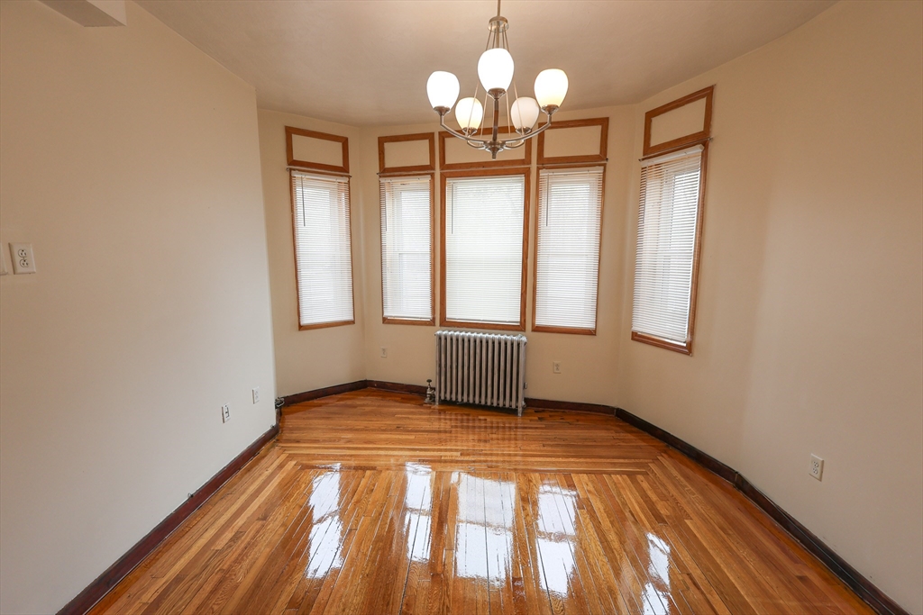 100 Seaver Street, Unit 2 Boston, MA 02121 - Photo 9 of 18 a view of an empty room with chandelier fan and wooden floor