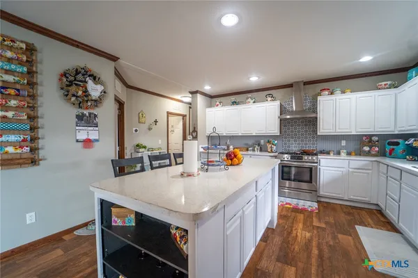 a large kitchen with stainless steel appliances granite countertop a lot of counter space and wooden floor
