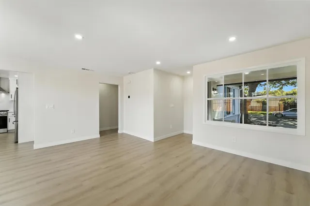 a view of an empty room with wooden floor and a window