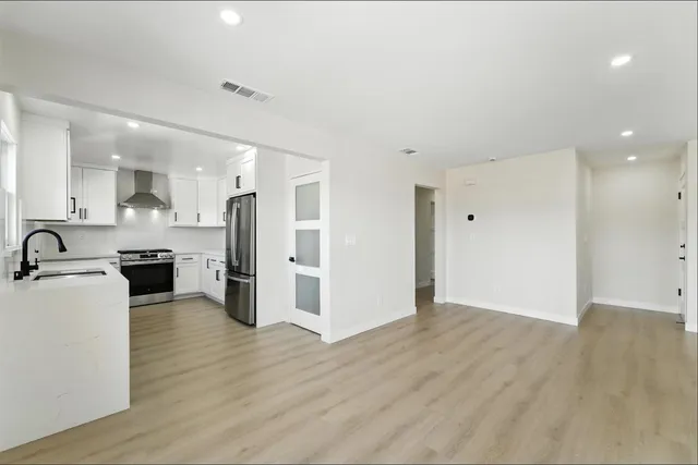 a view of a kitchen with stainless steel appliances wooden floor and windows