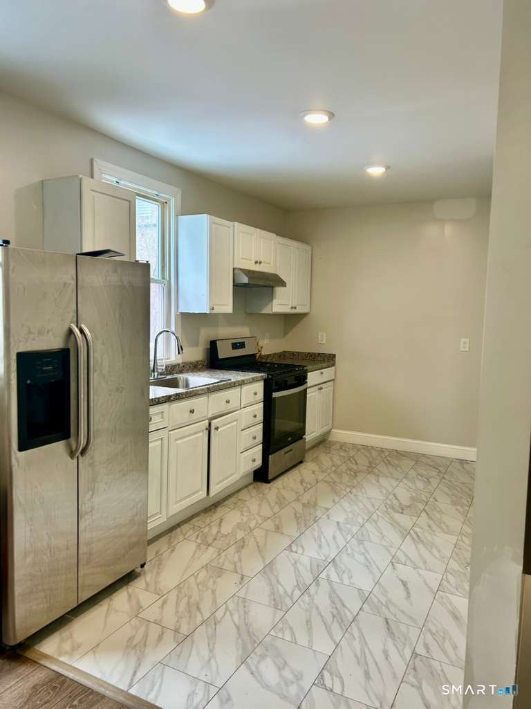 a kitchen with stainless steel appliances granite countertop a refrigerator sink and stove