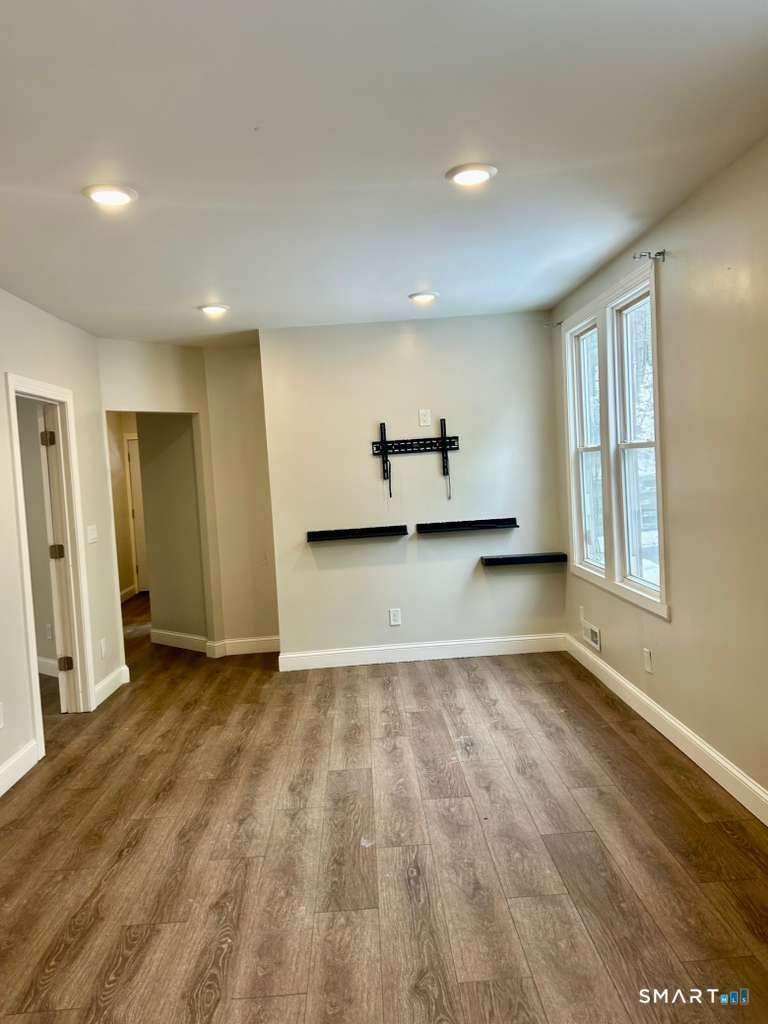124 Charles Street, Unit 2 Waterbury, CT 06708 - Photo 3 of 9 an empty room with wooden floor and windows
