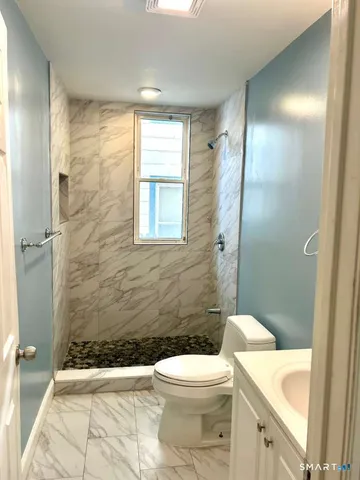 a bathroom with a granite countertop toilet a sink a shower and a mirror