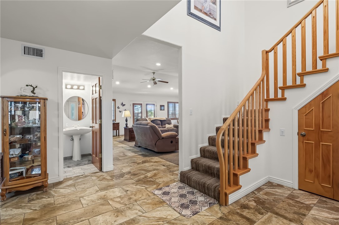 3342 Park Ridge Avenue Bullhead City, AZ 86429 - Photo 14 of 93 The property features a staircase with wooden banisters and carpeted steps, a porcelain pedestal sink in the bathroom, and stone tile flooring
