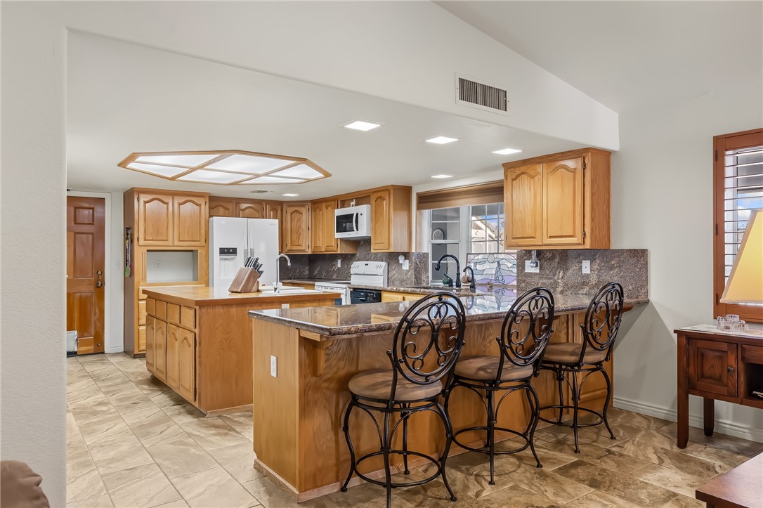 3342 Park Ridge Avenue Bullhead City, AZ 86429 - Photo 22 of 93 The kitchen features wood cabinetry, a central island with a breakfast bar, stone countertops, and tile flooring