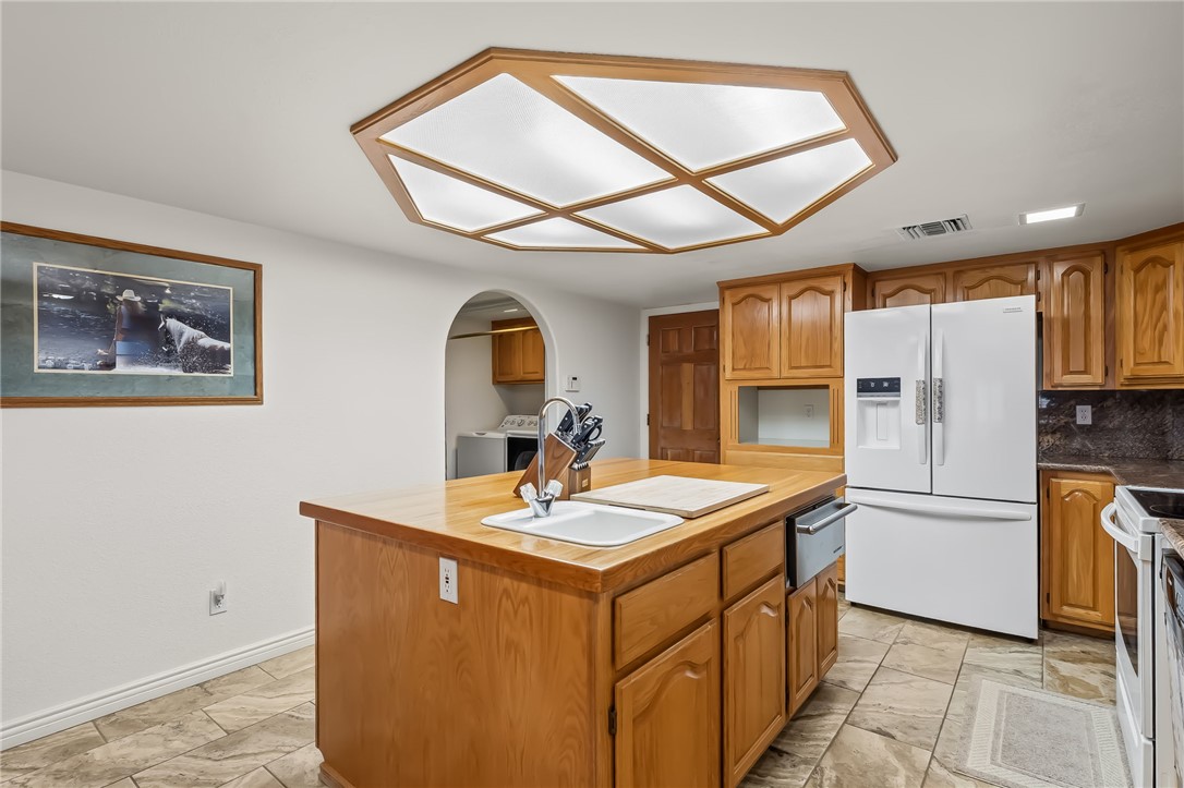 3342 Park Ridge Avenue Bullhead City, AZ 86429 - Photo 26 of 93 Kitchen featuring wood cabinetry, a center island with a sink, white appliances, and tiled flooring