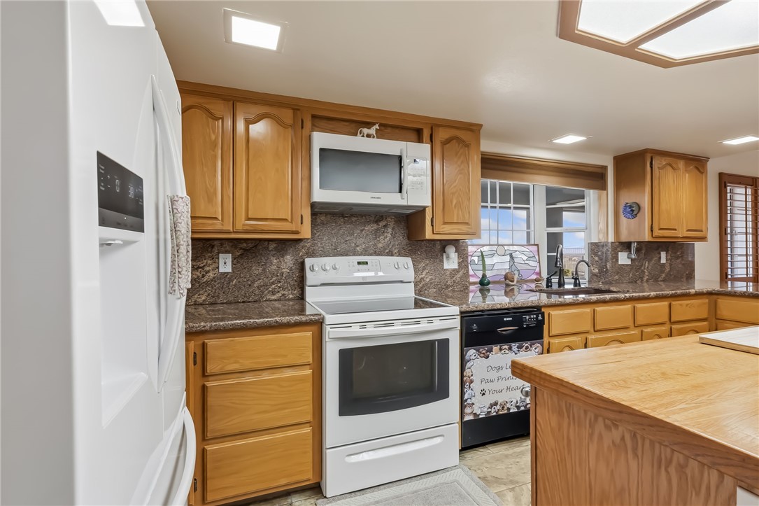 3342 Park Ridge Avenue Bullhead City, AZ 86429 - Photo 28 of 93 The kitchen features light wood cabinetry, a built-in microwave, a black dishwasher, and a refrigerator with a water and ice dispenser