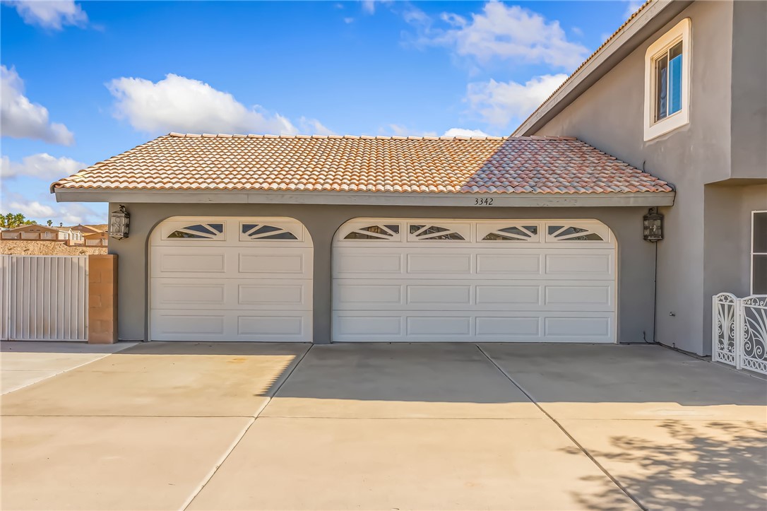 3342 Park Ridge Avenue Bullhead City, AZ 86429 - Photo 5 of 93 The property features an attached 3 car garage with arched entrances and decorative window inserts, garage fulol screensw,set against a stucco exterior and a tiled roof