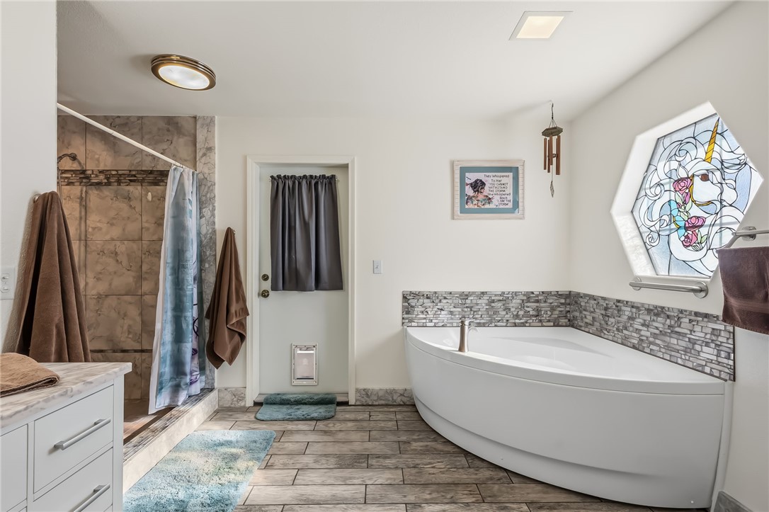 3342 Park Ridge Avenue Bullhead City, AZ 86429 - Photo 55 of 93 The bathroom features a corner soaking tub with a tiled surround, a separate tiled shower, and wood-look tile flooring