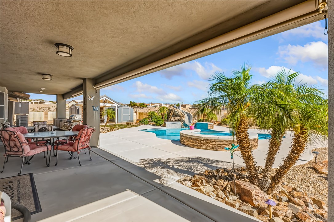 3342 Park Ridge Avenue Bullhead City, AZ 86429 - Photo 72 of 93 The property features a covered patio with recessed lighting, an outdoor pool with a slide, and a built-in stone-clad hot tub