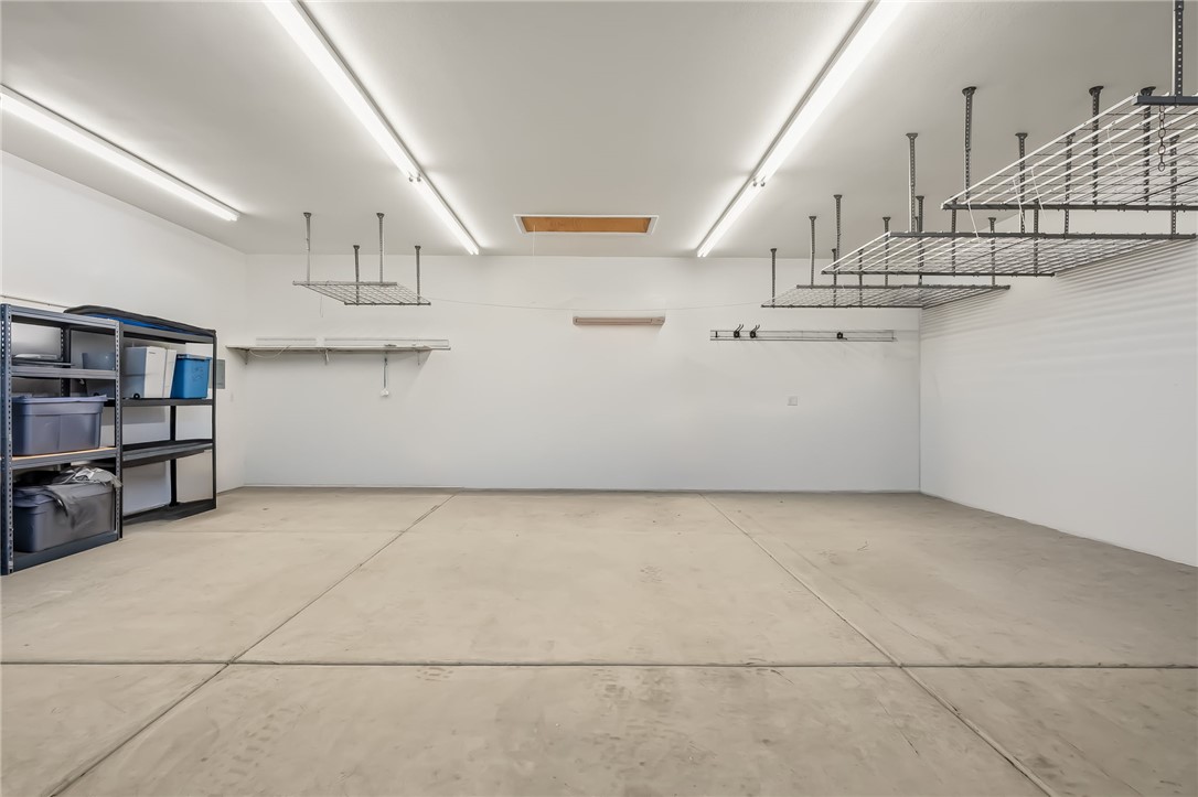 3342 Park Ridge Avenue Bullhead City, AZ 86429 - Photo 76 of 93 Detached garage features concrete flooring, overhead fluorescent lighting, and extensive storage solutions including shelving units and ceiling-mounted racks