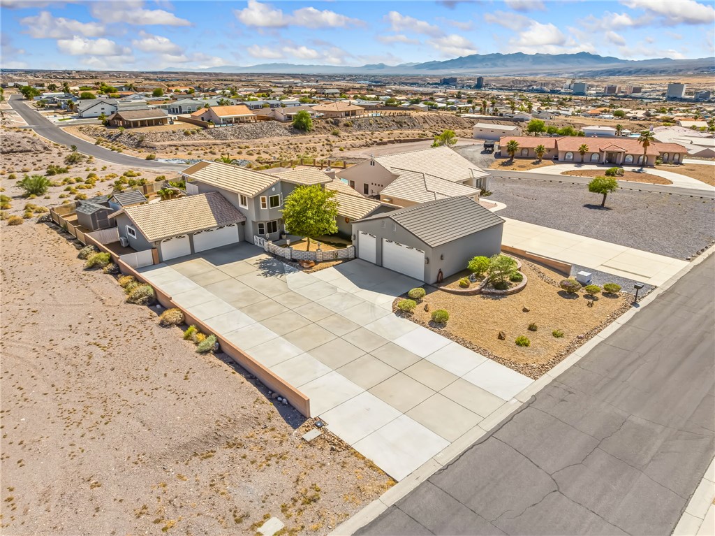 3342 Park Ridge Avenue Bullhead City, AZ 86429 - Photo 80 of 93 The property features an extensive paved driveway, a well-maintained exterior with a light-colored roof, and a detached garage