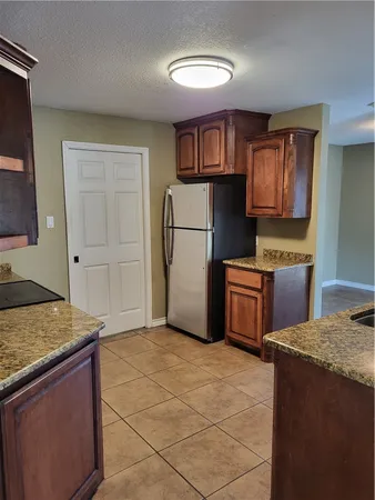 a kitchen with granite countertop a refrigerator and a stove top oven