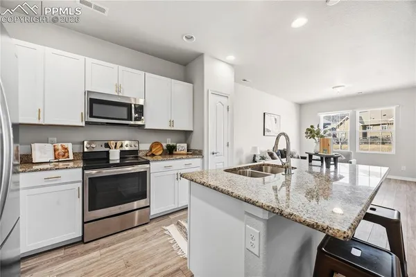 a kitchen with kitchen island granite countertop a stove sink and microwave