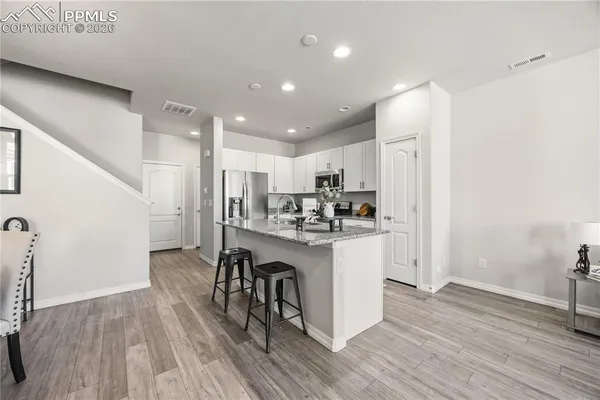 a kitchen with stainless steel appliances granite countertop a refrigerator a stove and a wooden floors