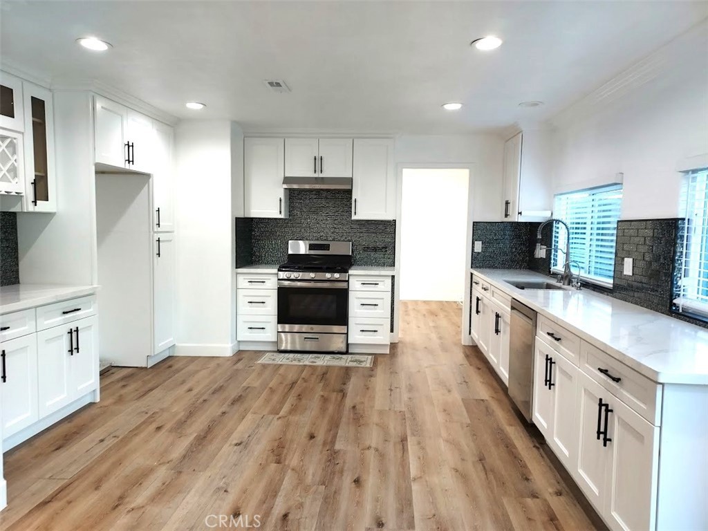 8803 Hummingbird Avenue Fountain Valley, CA 92708 - Photo 29 of 43 a large kitchen with stainless steel appliances granite countertop a stove top oven a refrigerator a sink and dishwasher with wooden floor