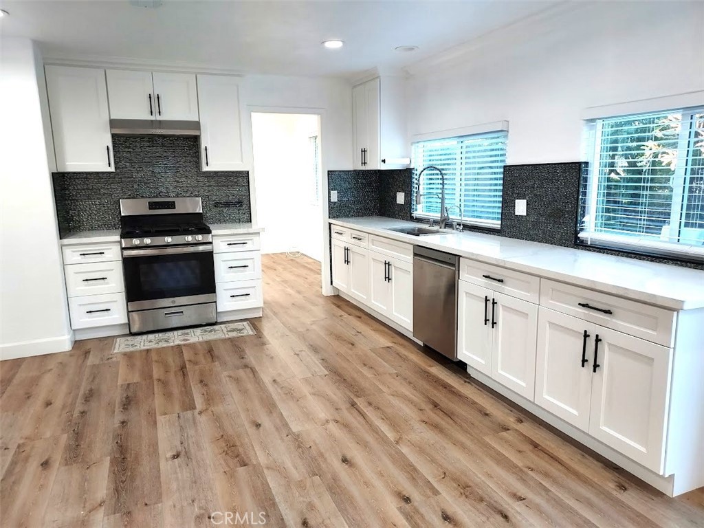 8803 Hummingbird Avenue Fountain Valley, CA 92708 - Photo 30 of 43 a kitchen with stainless steel appliances granite countertop a stove a sink and white cabinets