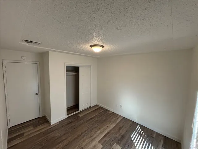 a view of an empty room with wooden floor and closet