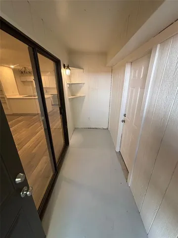 a view of kitchen and empty room with wooden floor