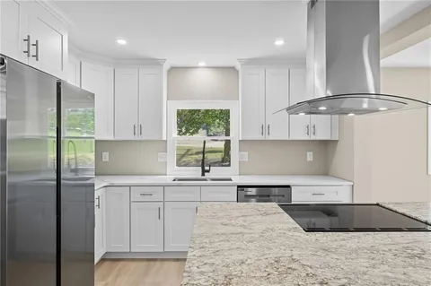 a kitchen with stainless steel appliances granite countertop a sink refrigerator and cabinets