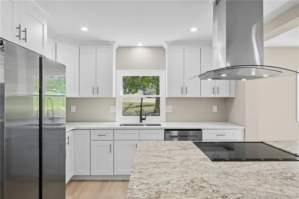 a kitchen with stainless steel appliances granite countertop a sink refrigerator and cabinets