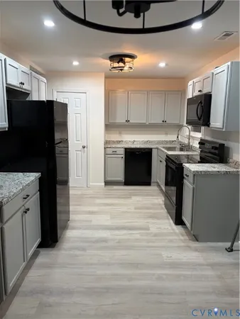 a kitchen with stainless steel appliances granite countertop a stove top oven a refrigerator and a sink