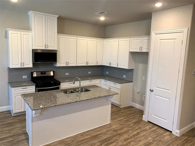 a kitchen with granite countertop a sink and a stove top oven