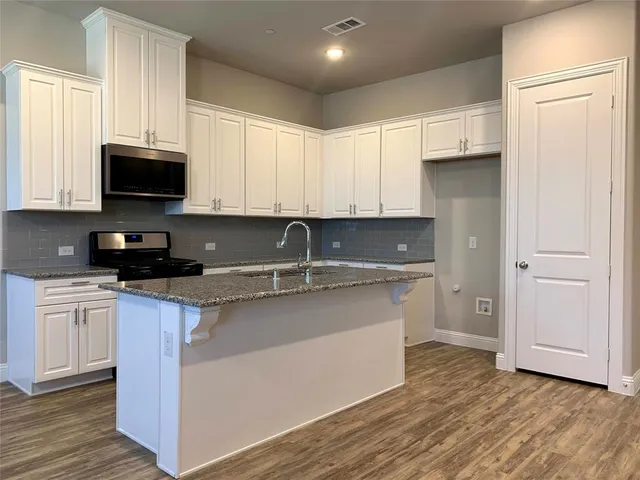 a kitchen with stainless steel appliances granite countertop a stove a sink and a microwave