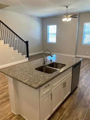 a kitchen with stainless steel appliances granite countertop a sink dishwasher and stove with wooden floor