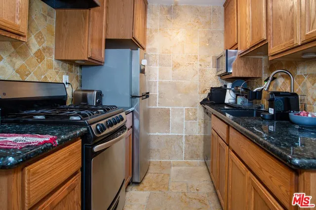 a kitchen with stainless steel appliances granite countertop a stove a sink and a microwave