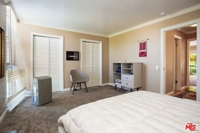 a bedroom with a bed a chair and large window