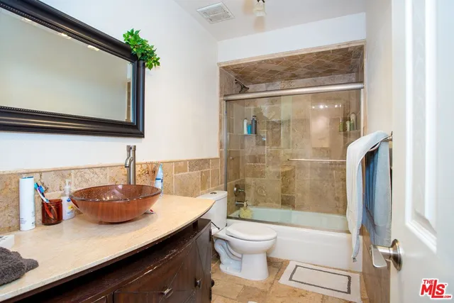a bathroom with a granite countertop sink toilet and shower