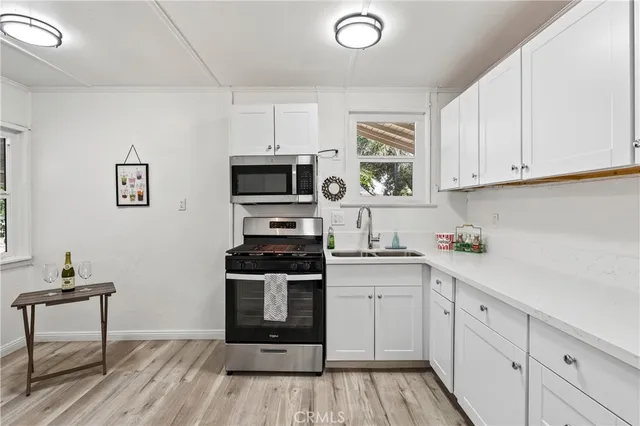 a kitchen with stainless steel appliances a stove a sink cabinets and a wooden floor