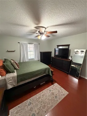 a bedroom with a bed a couch and a flat tv screen on a dresser