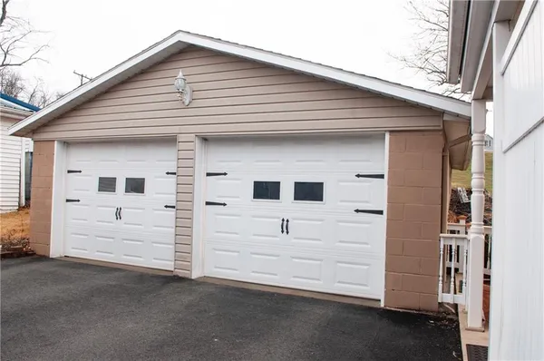 a view of a white house with a small yard and large tree