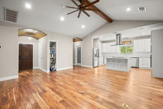 a view of an empty room with kitchen and window