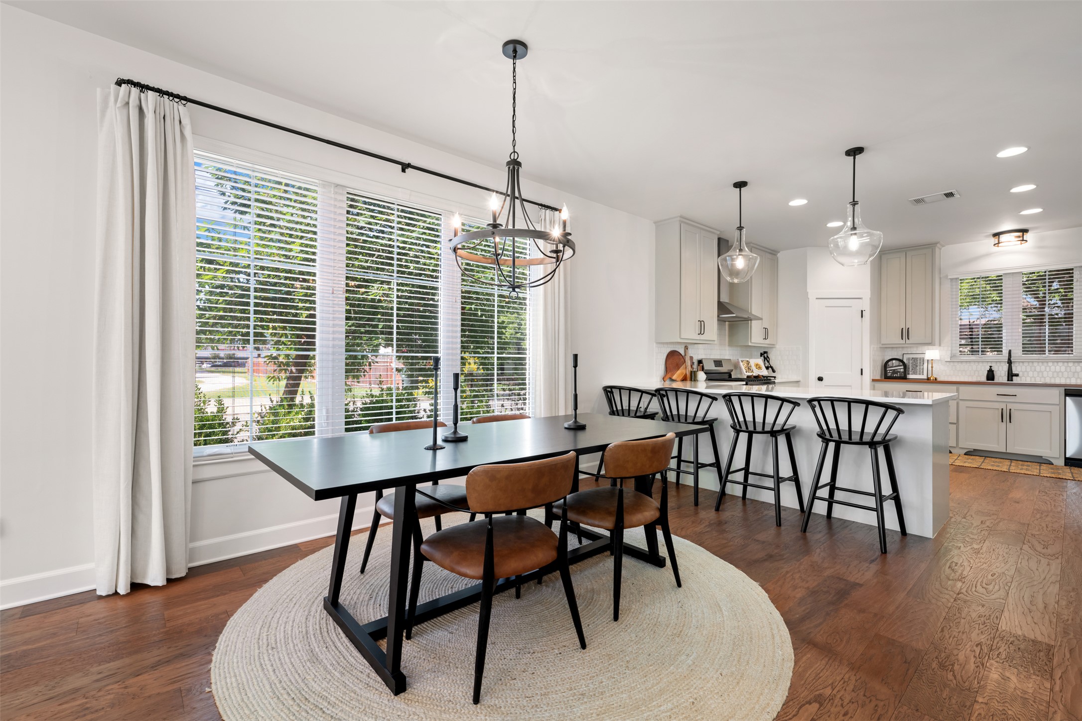 1301 West Street Georgetown, TX 78626 - Photo 10 of 40 Hardwood floors stretch across this open-concept dining area and kitchen, illuminated by recessed lighting and a large window.