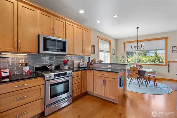 a kitchen with granite countertop a stove a sink and a microwave