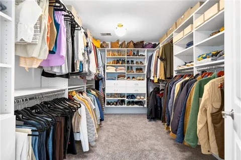 a view of walk in closet with clothes and shoes