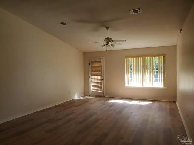 a view of an empty room with a window and wooden floor