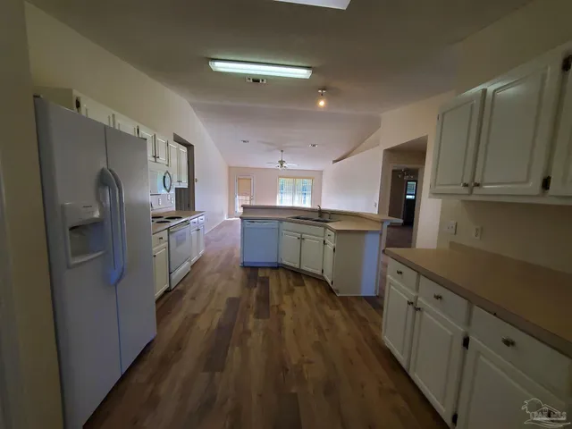 a kitchen with stainless steel appliances granite countertop refrigerator a sink dishwasher a stove top oven a refrigerator with wooden floors